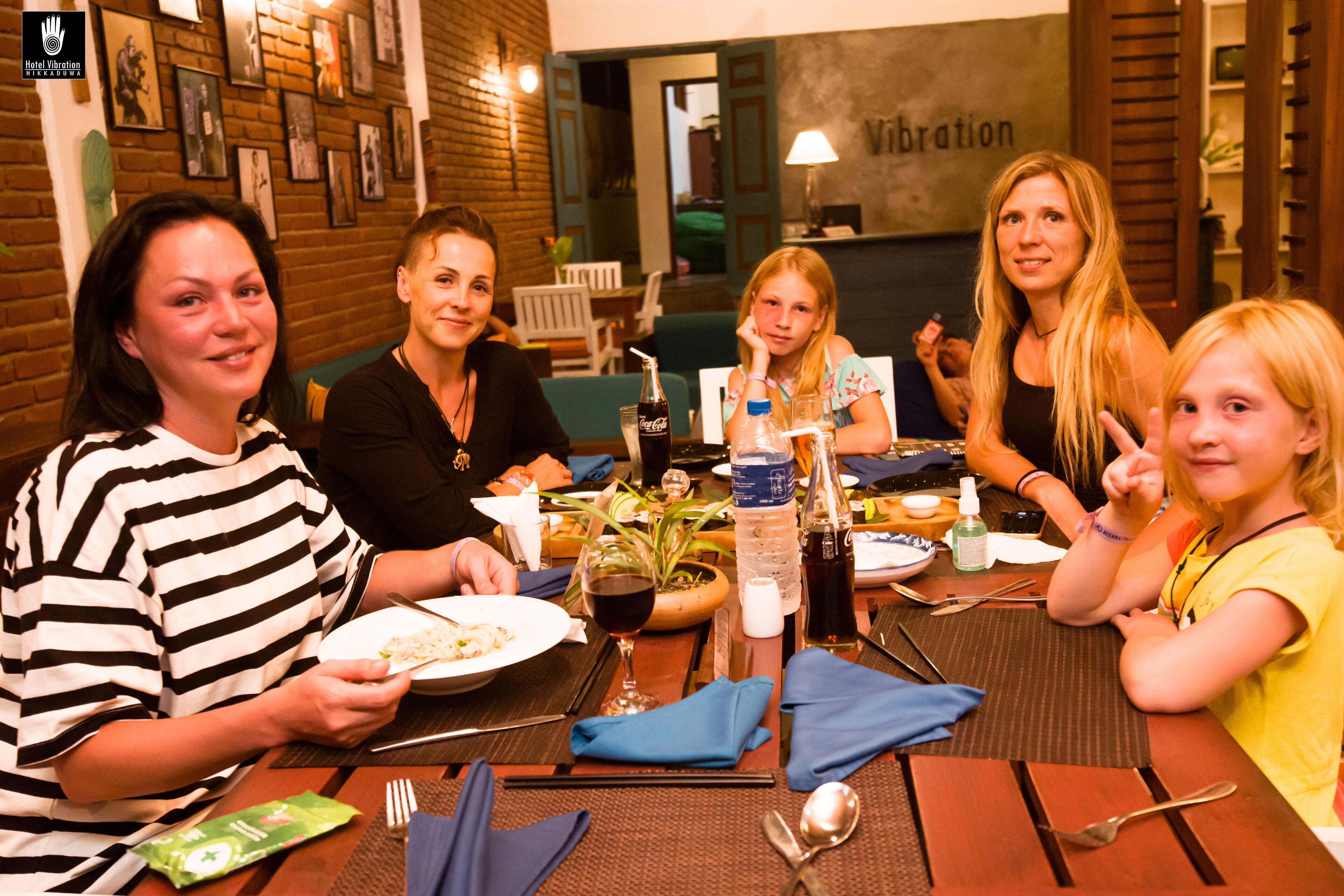 A group of people dining at a restaurant with a brick wall and framed pictures in the background.