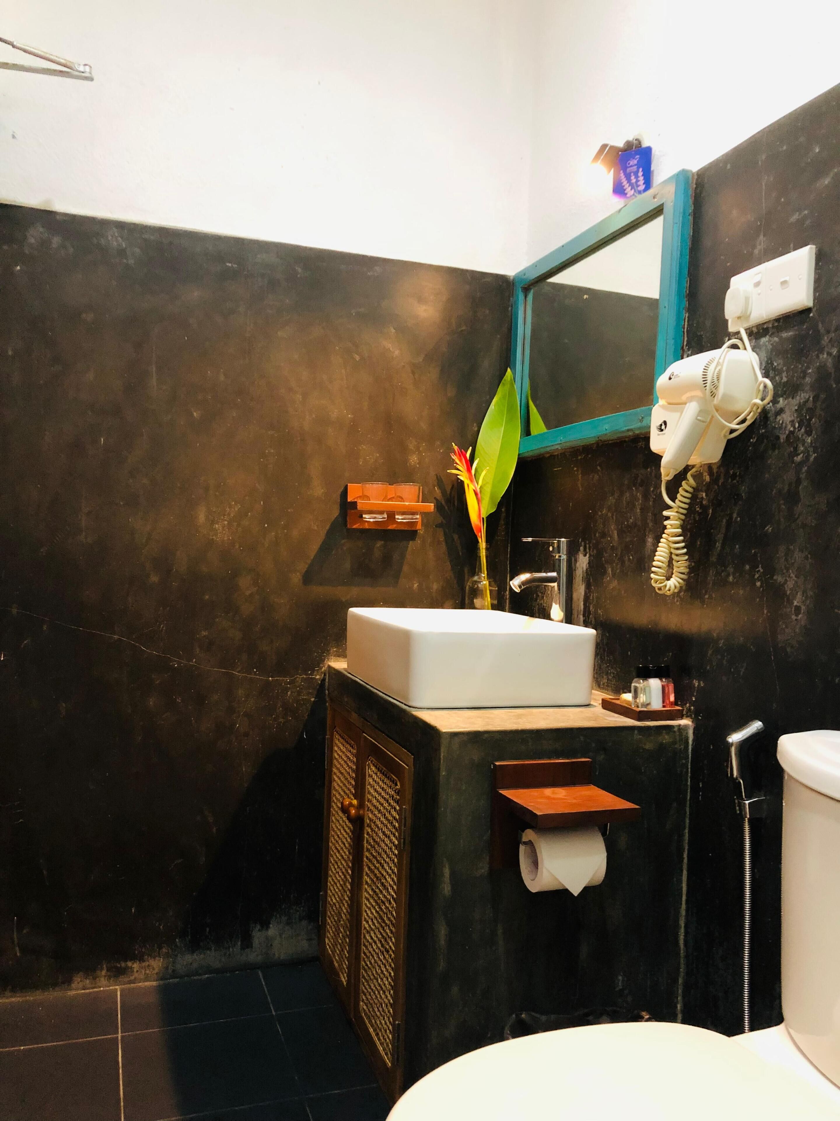 A bathroom with a white sink, a mirror, a hairdryer, and a toilet.