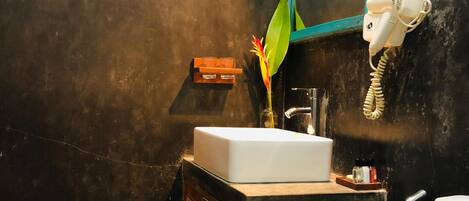 A bathroom with a white sink, a mirror, a hairdryer, and a toilet.