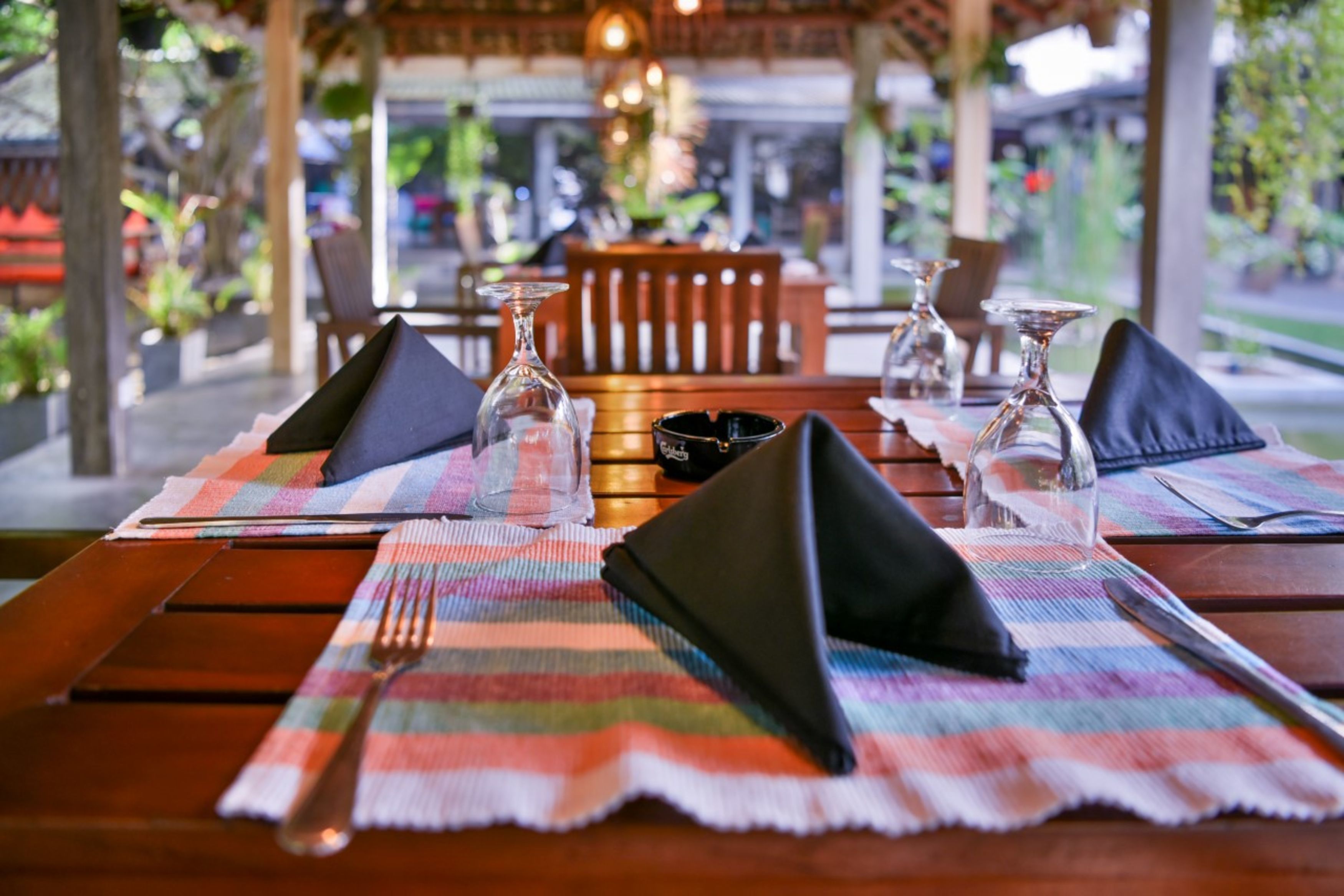 A table set with a plaid placemat, black napkins, and clear glassware.