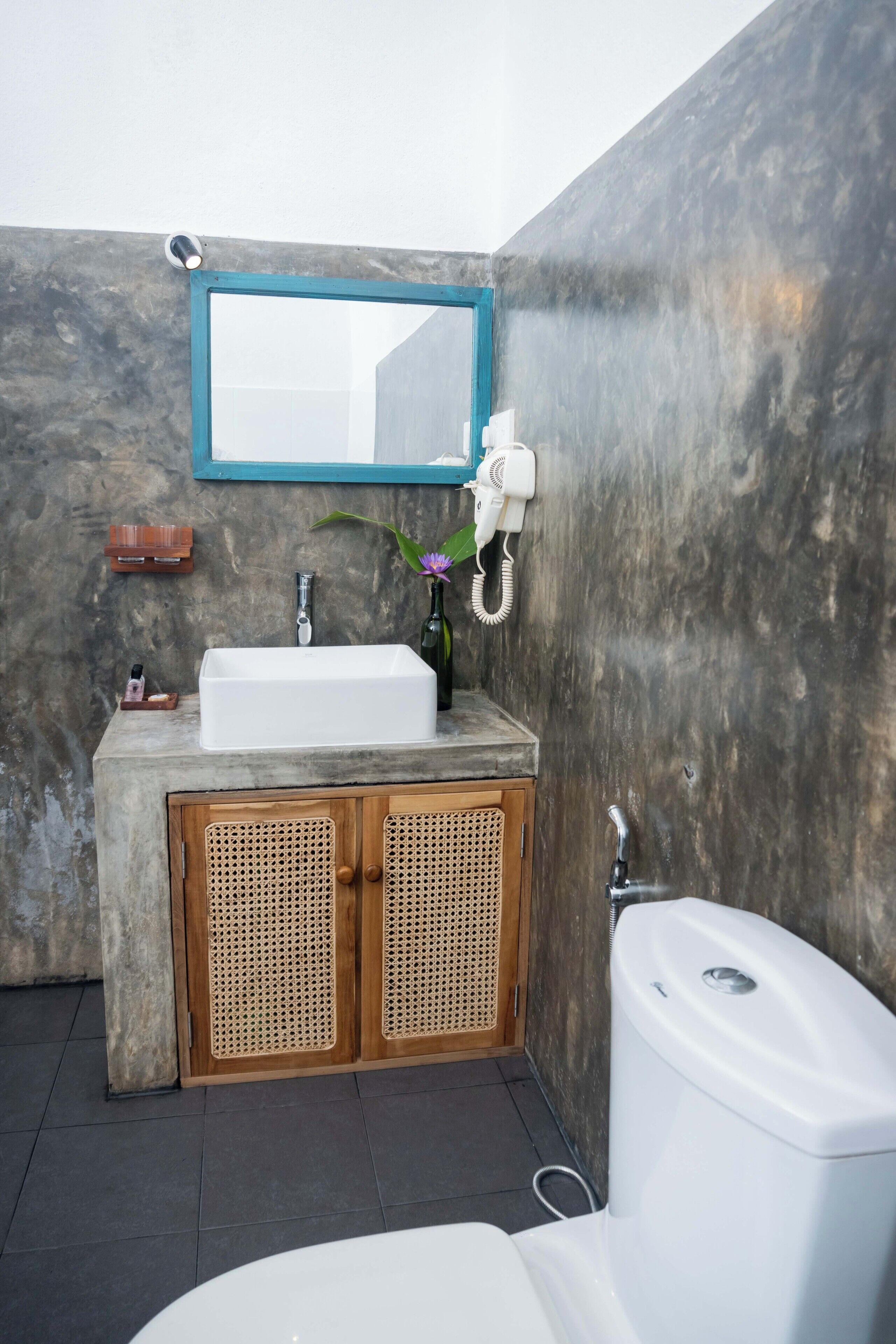 Une salle de bain avec un lavabo blanc, des meubles en bois, un miroir et des toilettes.