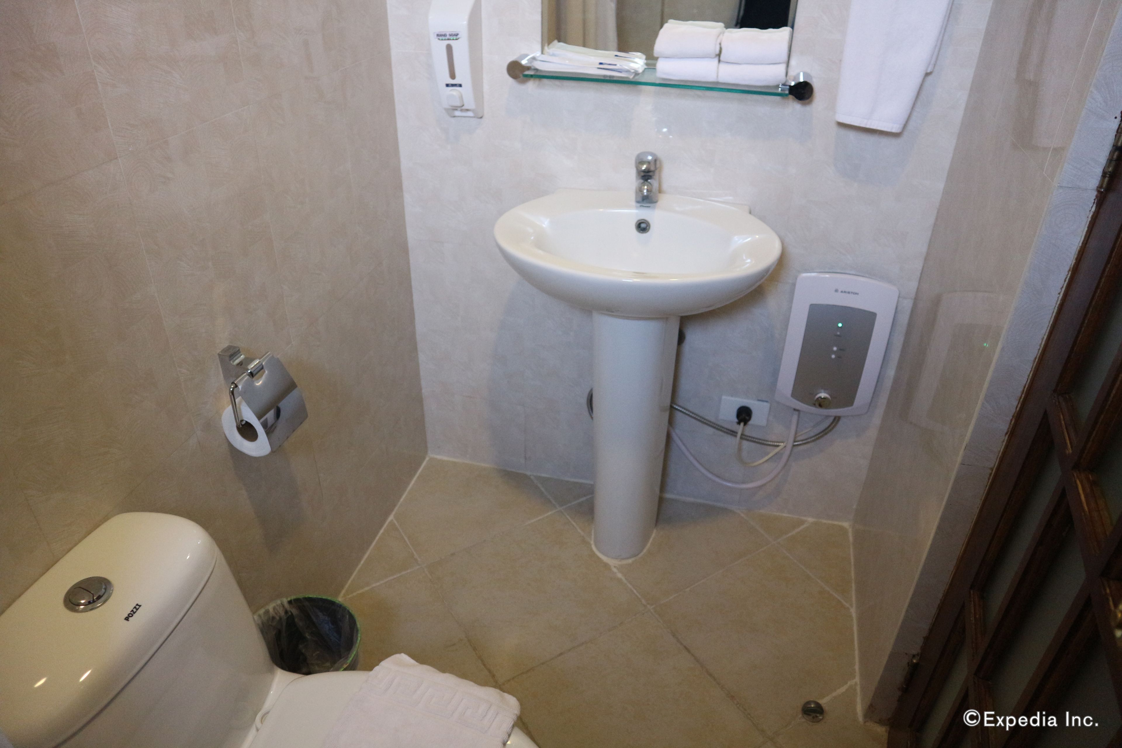 A bathroom with a white sink, toilet, and a glass shelf above the sink.