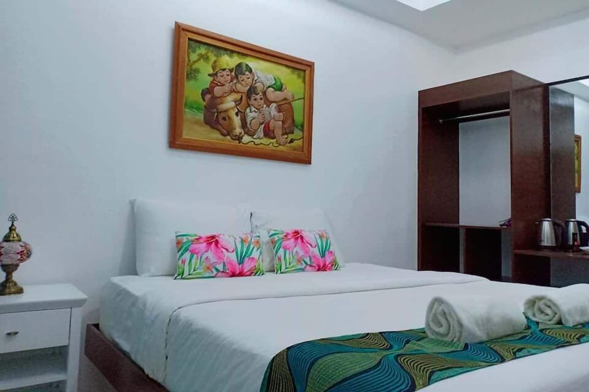 Quarto de hotel com cama, mesa de cabeceira, espelho e um quadro na parede.