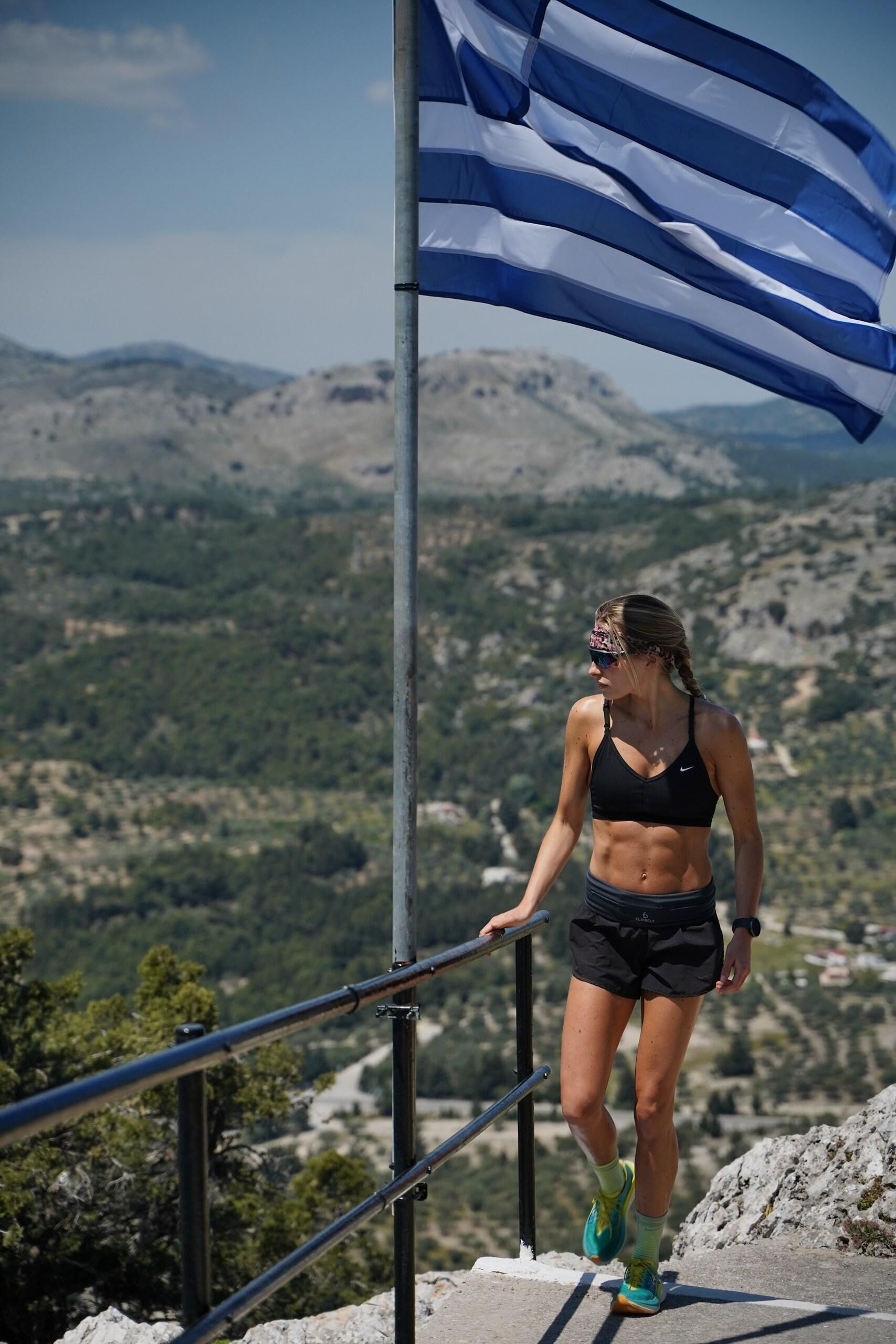 A person walking on a metal railing with a mountainous landscape in the background.