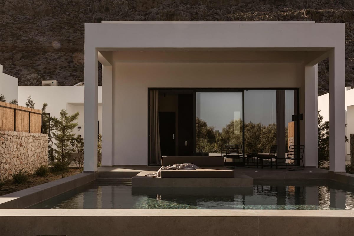 A modern outdoor pool area with a seating area and a covered section.