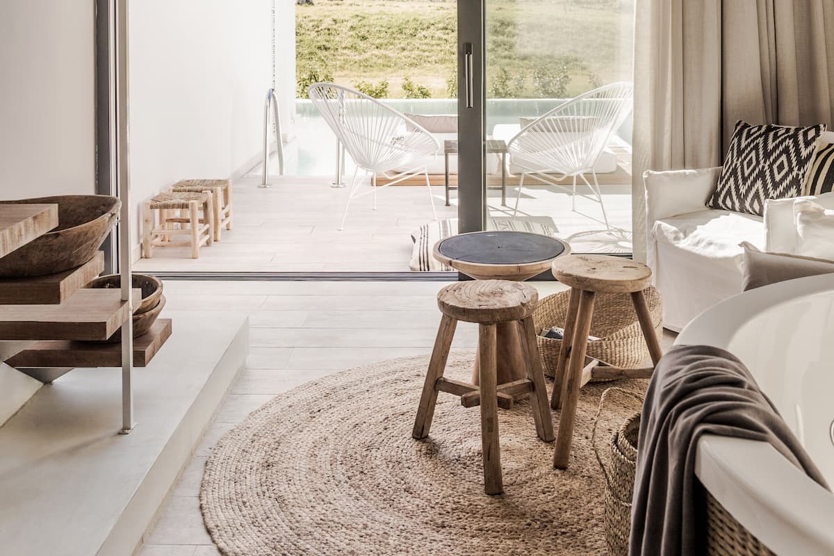 A modern living room with a large window, a woven light fixture, and a view of a mountainous landscape.