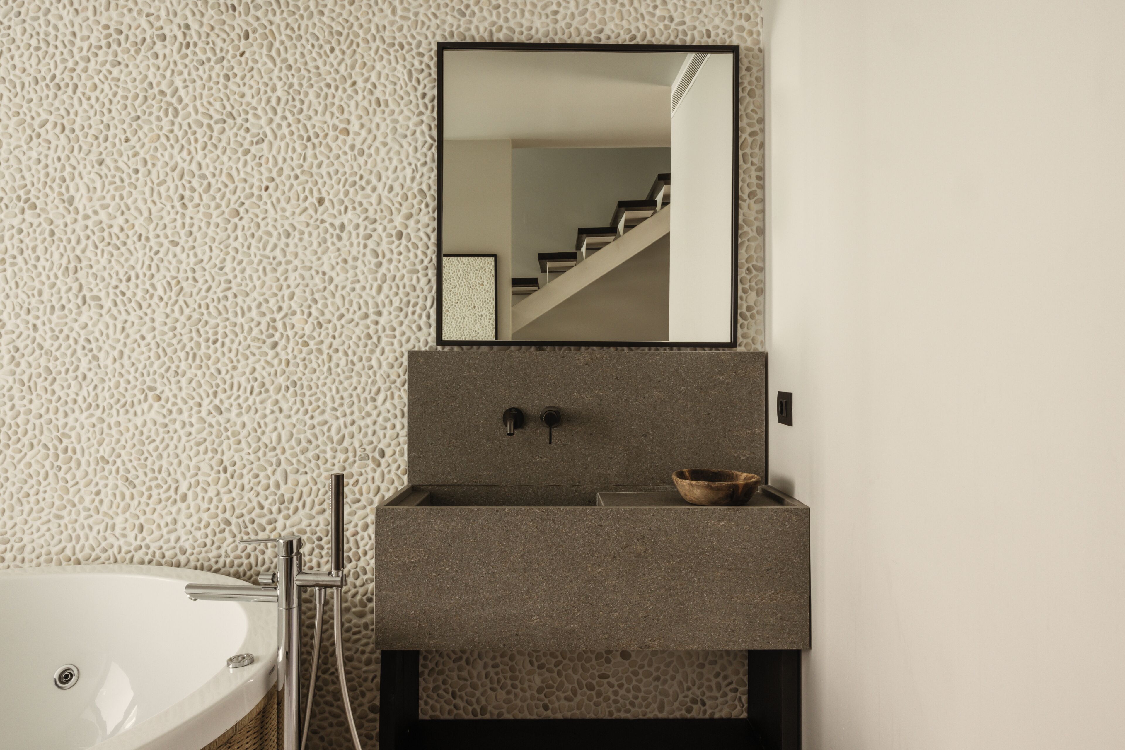 A bathroom with a freestanding bathtub, a sink with a bowl, and a mirror above the sink.