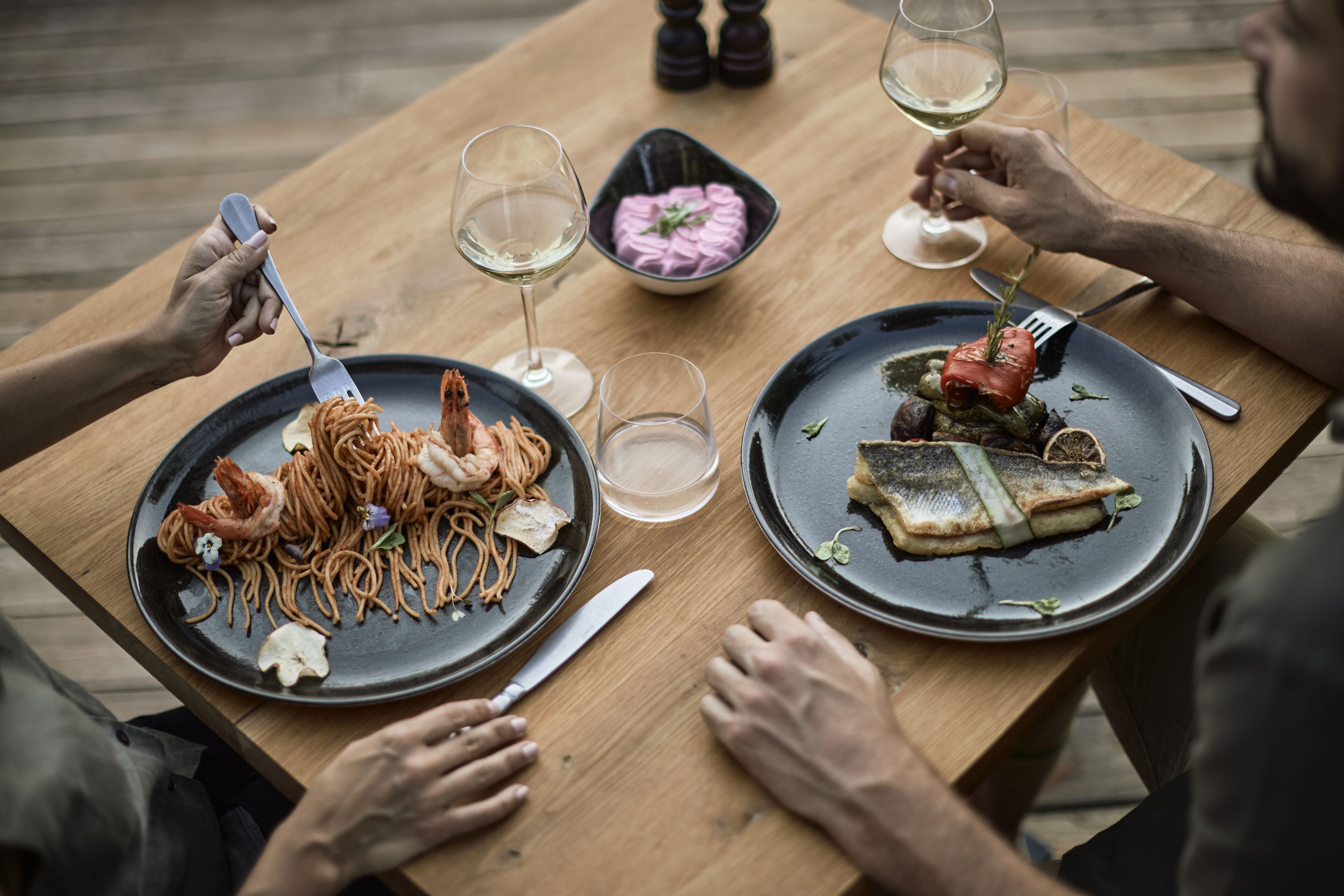 A wooden table with two plates of food, a fork, and a knife.