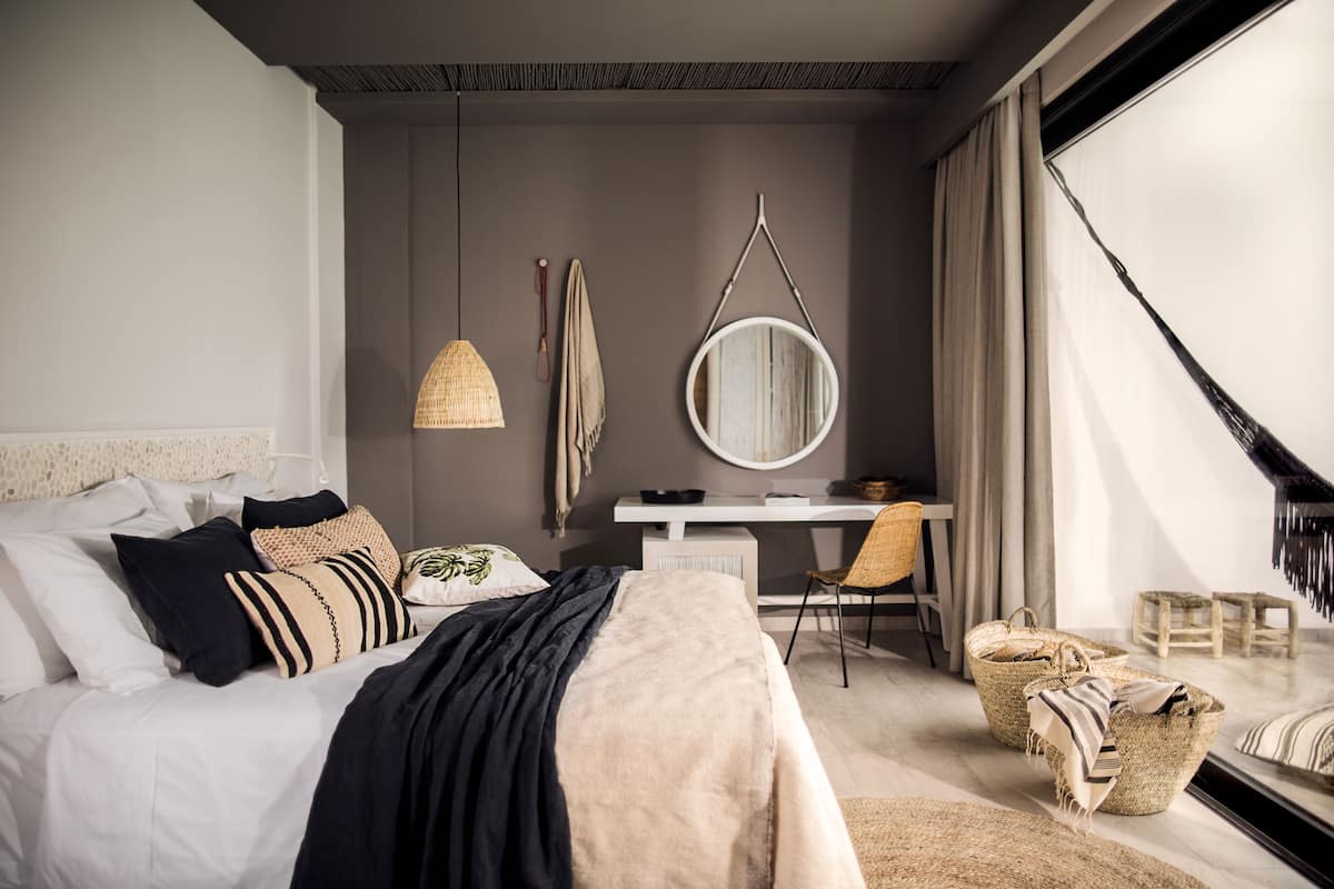 A modern bedroom with a bed, desk, and large window.