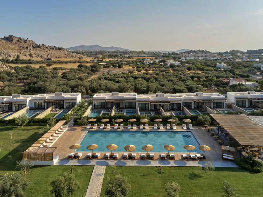 Een resort met een groot zwembad, ligbedden en uitzicht op het omliggende landschap.