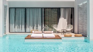 A modern pool area with two lounge chairs, a white chair, and a small table.