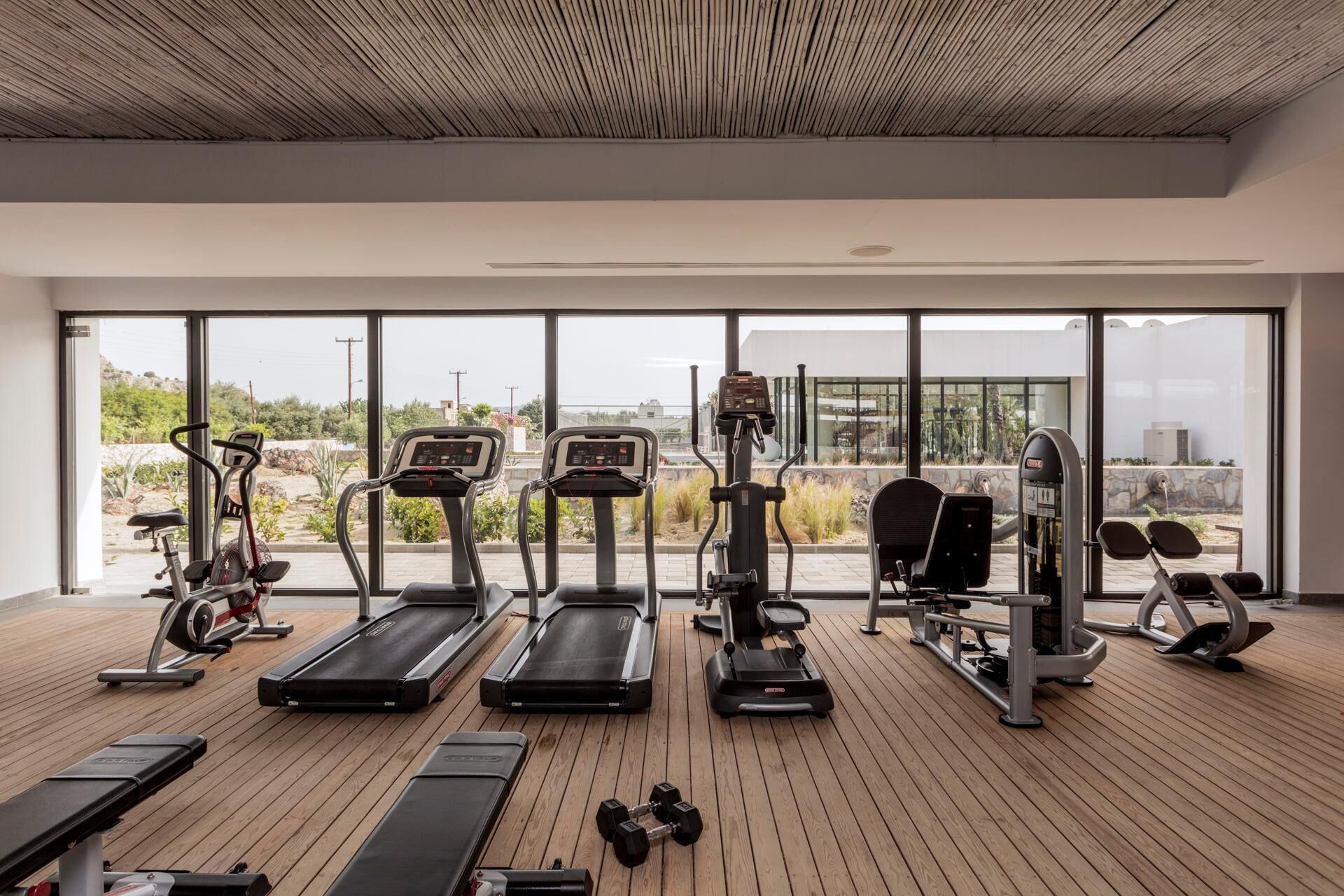 A modern gym with treadmills, elliptical machines, and weight equipment.