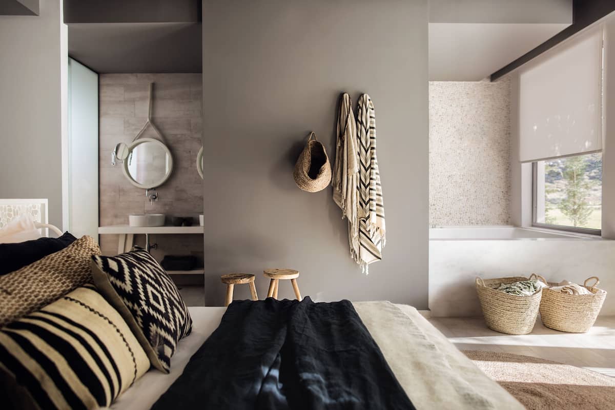A modern bedroom with a bed, pillows, a hanging basket, and a window with a view.