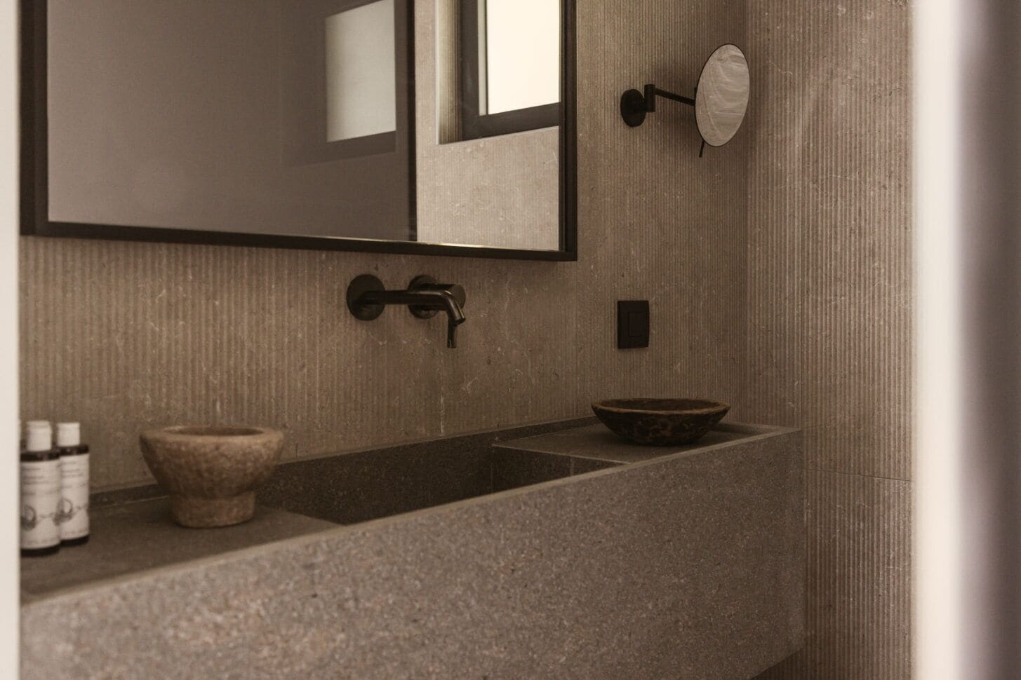 A bathroom with a large mirror, a sink, a basin, and a towel rack.