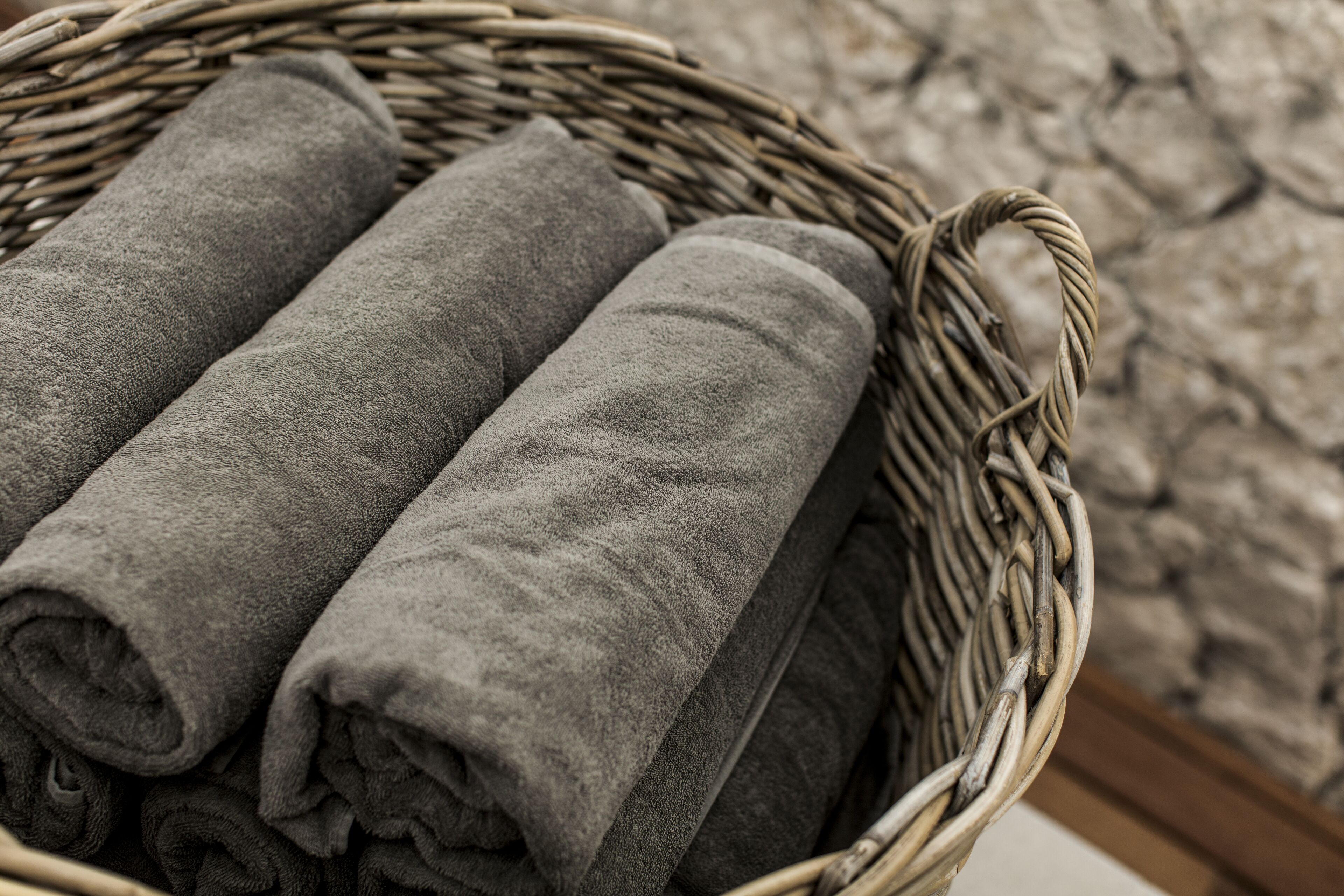 A wicker basket containing rolled gray towels.
