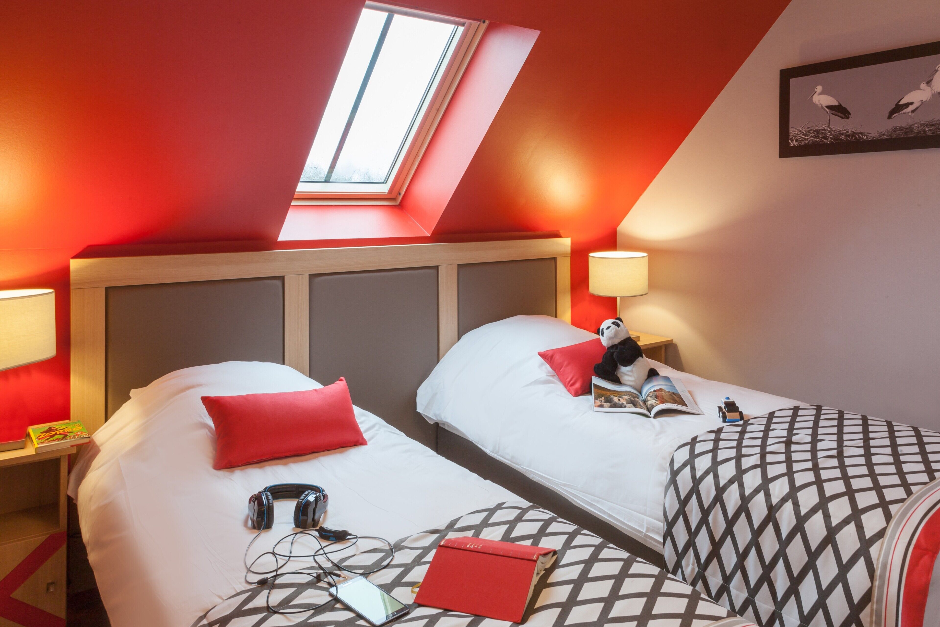 Ein Hotelzimmer mit zwei Betten, einem Oberlicht und einem gerahmten Bild an der Wand.