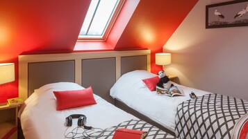 Ein Hotelzimmer mit zwei Betten, einem Oberlicht und einem gerahmten Bild an der Wand.