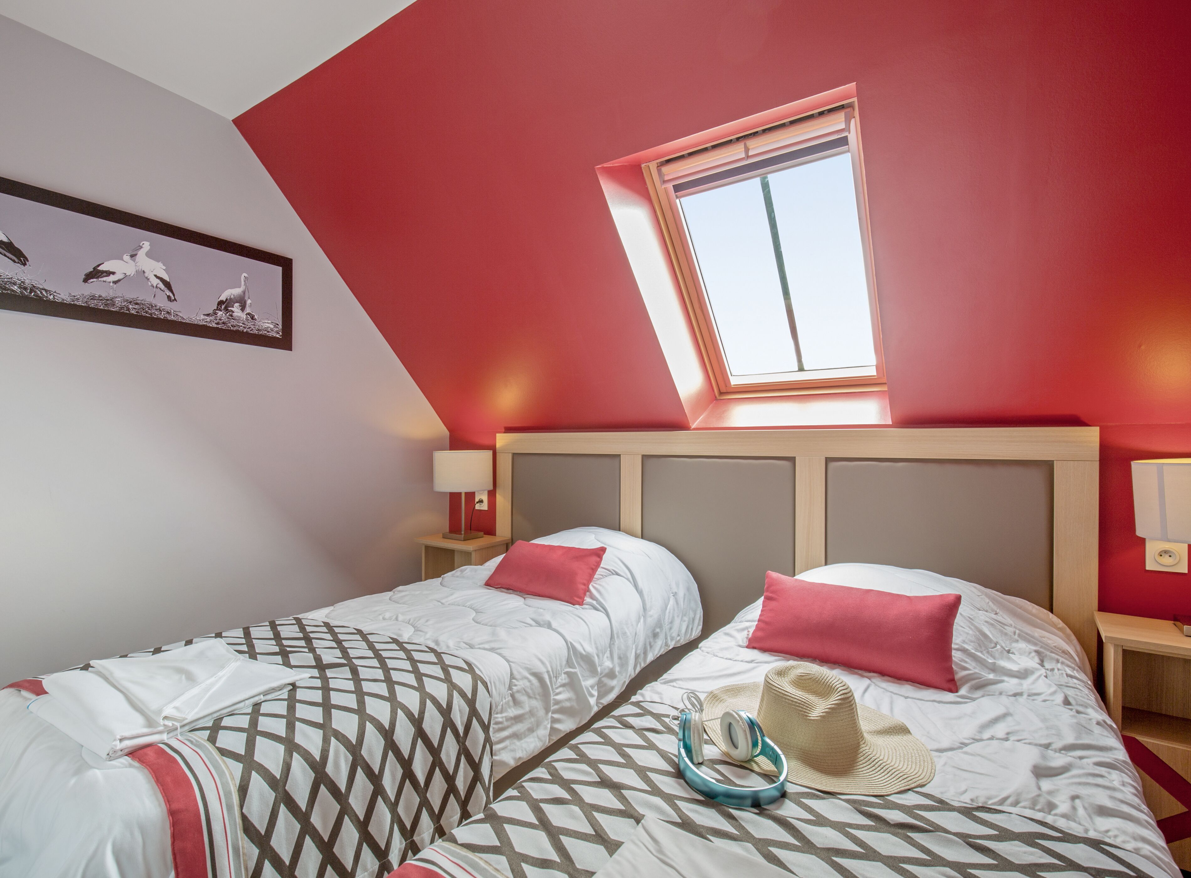 Un dormitorio con dos camas, un tragaluz y un cuadro en la pared.