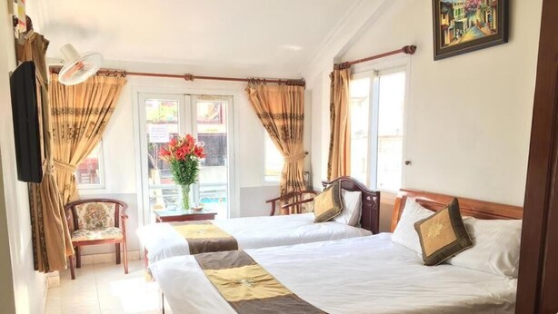 A hotel room with two beds, a chair, a table, and a window with curtains.