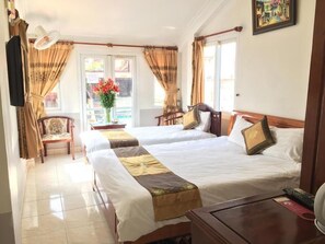 Une chambre d’hôtel avec deux lits, une chaise, une table et une fenêtre avec des rideaux.