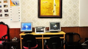 A room with two desktop computers, a printer, and a framed picture on the wall.