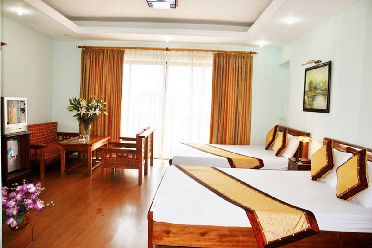 A hotel room with two beds, a desk, a chair, a television, and a painting on the wall.