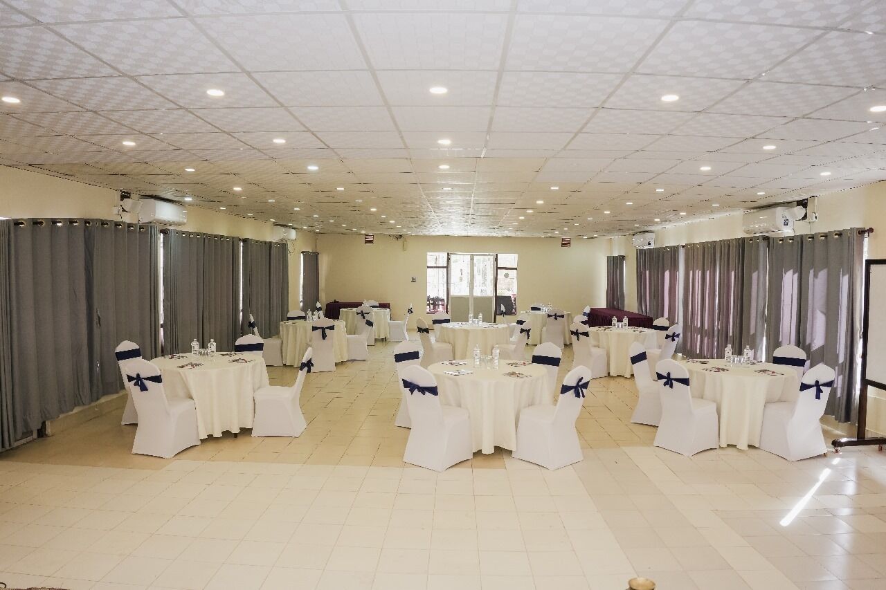 A banquet hall with round tables and white chairs, arranged in a U-shape.