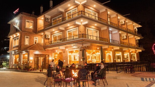 Een meerlaags gebouw met terras en vuurkorf.