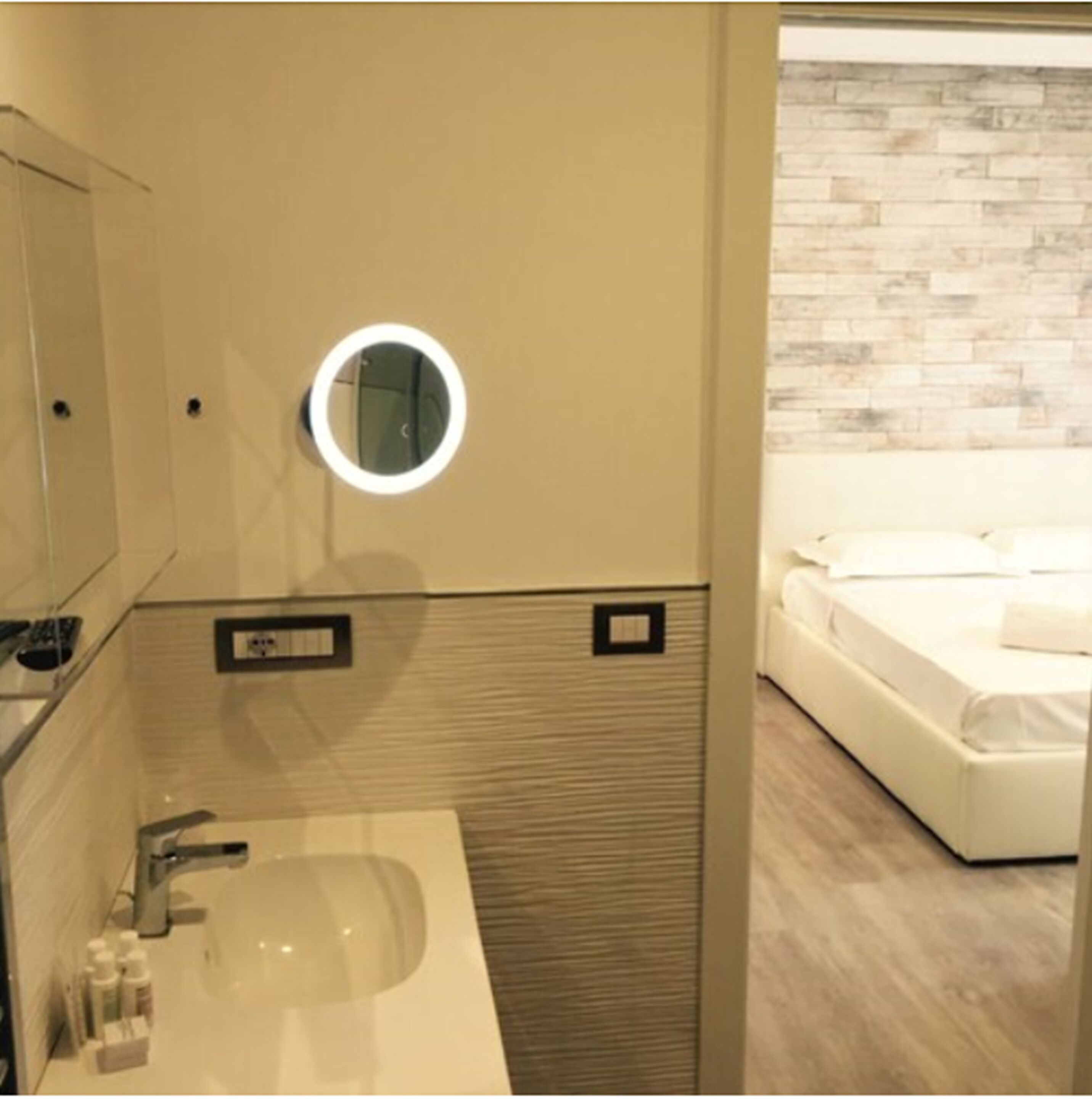 Ein Badezimmer mit rundem Spiegel, Waschbecken und Toilettenartikeln.