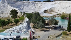 Un paisaje escalonado con una masa de agua cristalina, senderos y un pequeño pabellón.