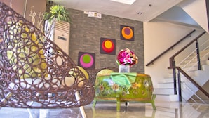 A modern interior with a staircase, a decorative wall, and a sofa with a vase of flowers. - Canberry Hotel (Cebu City)