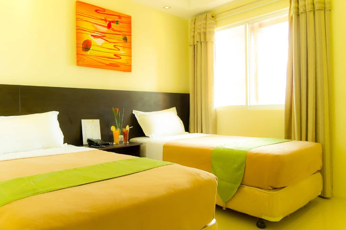 A hotel room with two beds, a nightstand with a phone and a glass of orange juice, and a painting on the wall.