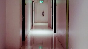 A long, narrow hallway with white walls and a shiny tiled floor, leading to a door at the end. - Canberry Hotel (Cebu City)