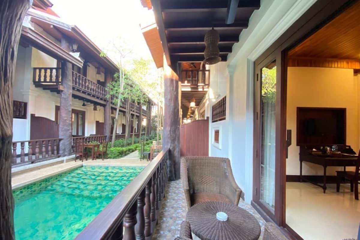 Un bâtiment de style traditionnel doté d’un balcon donnant sur une piscine, de meubles en bois et d’un coin repas.