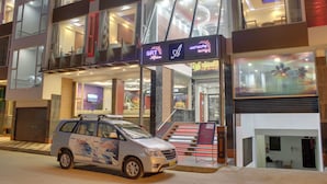 Un hotel con diseño moderno, que cuenta con una zona de servicio de coches, una escalera con iluminación roja y un cartel sobre la entrada.