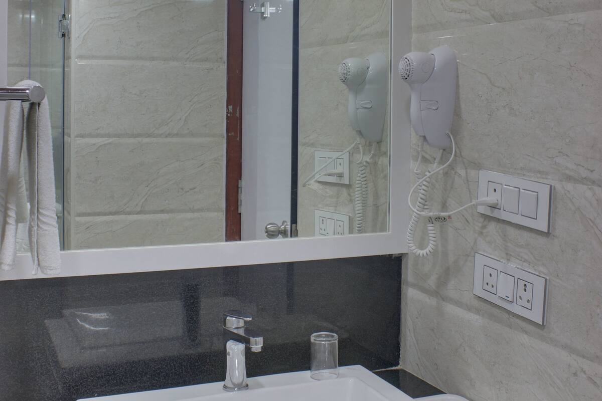 A bathroom with a white sink, a mirror, a hairdryer, and a towel rack.