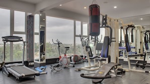 Un gimnasio con diverso equipo de ejercicio, amplias ventanas y un saco de boxeo.