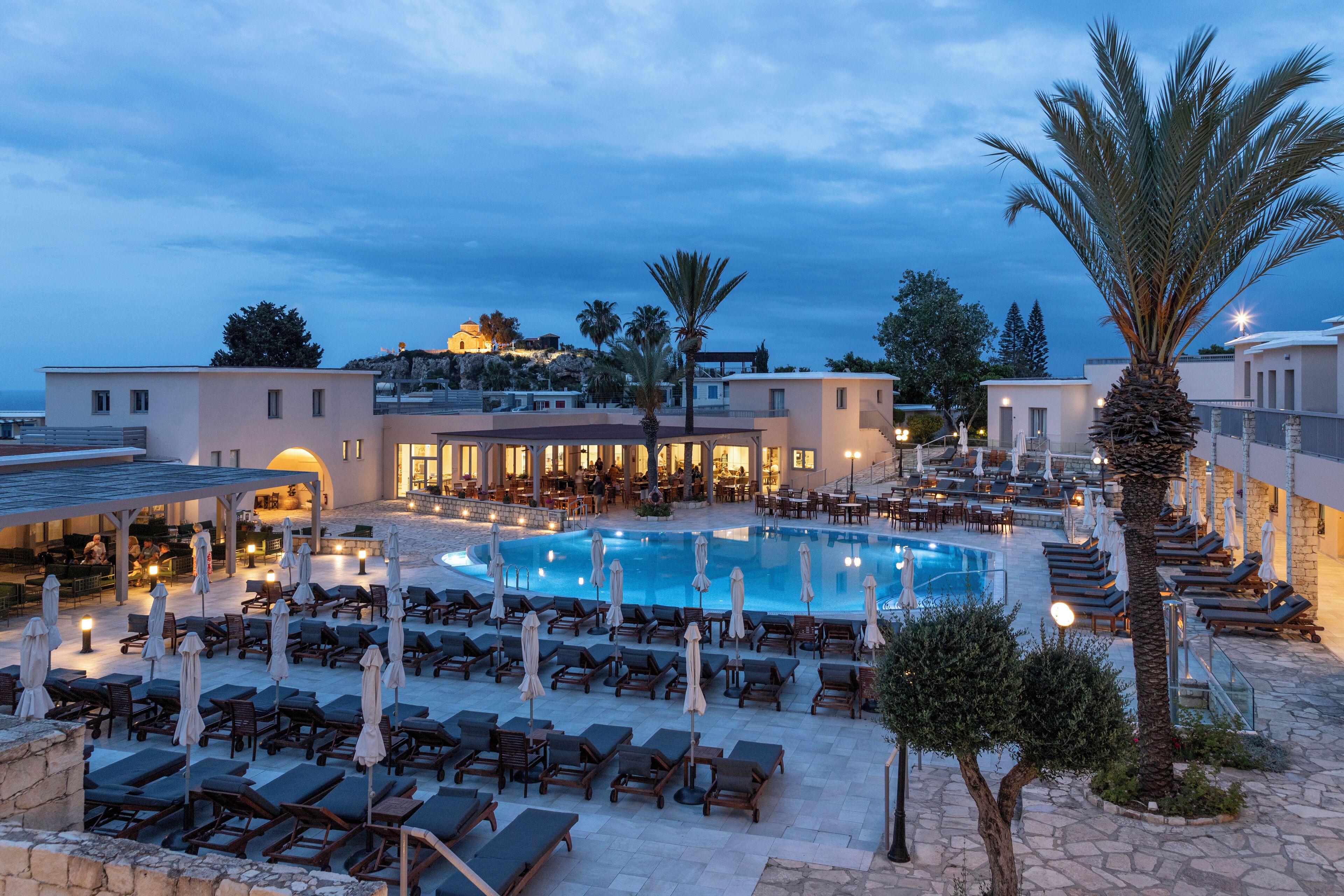 A resort pool area with sun loungers, umbrellas, and a large pool.
