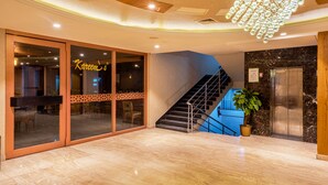 A hotel lobby with a marble floor, a staircase, a chandelier, and a sign reading "Karim's".