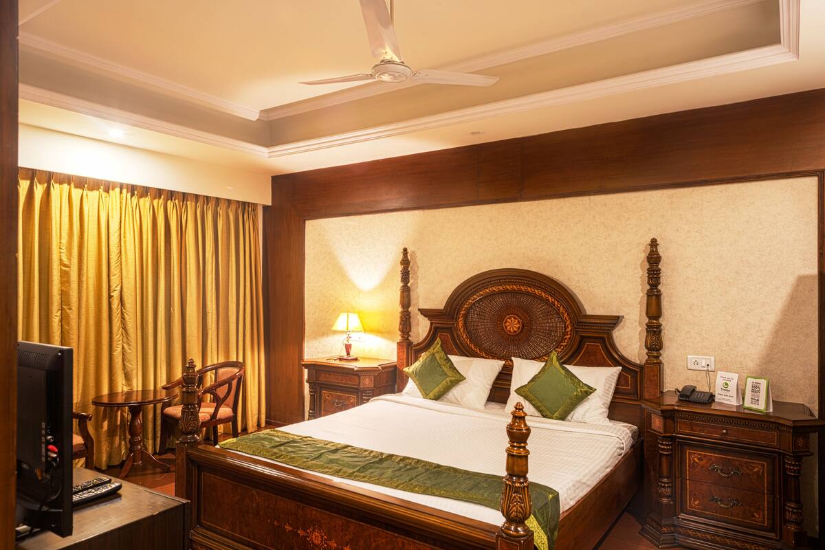 A hotel room with a large bed, a television, a desk, and a chair.