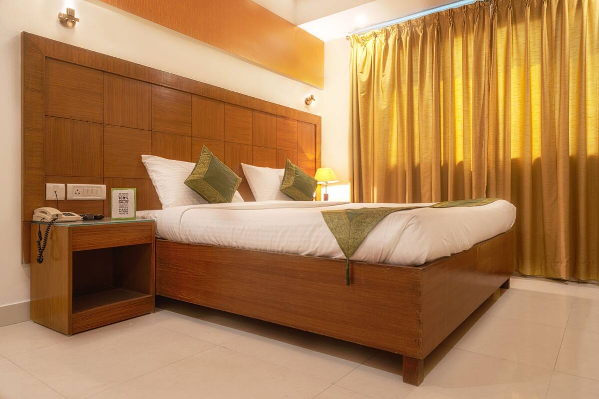 A hotel room with a wooden bed, a bedside table with a phone, and a lamp.