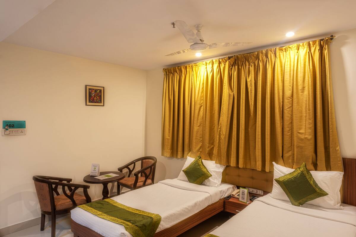 A hotel room with two beds, a desk, and a chair.