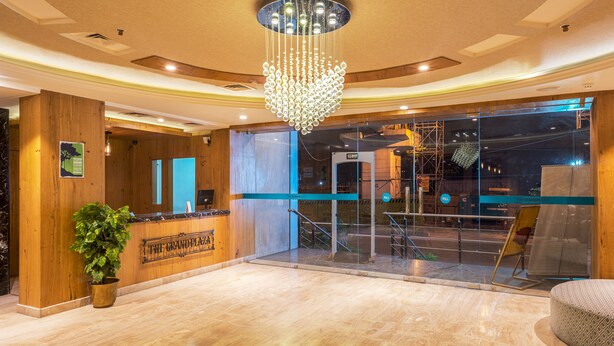 A lobby with a reception desk, a chandelier, and a staircase leading to an upper level.