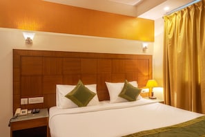 A hotel room with a wooden headboard, a bedside table with a lamp, and a telephone.