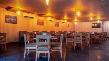 A conference room with multiple tables and chairs, air conditioning units, and wall-mounted artwork.