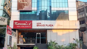 A hotel with a 'NOW OPEN' sign, 'Kareem's' restaurant, and 'Hotel Grand Plaza' signage.