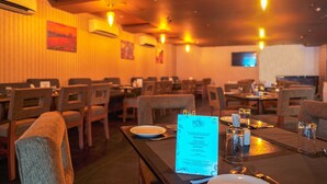 A restaurant with tables set for dining, a menu on the table, and a television on the wall.