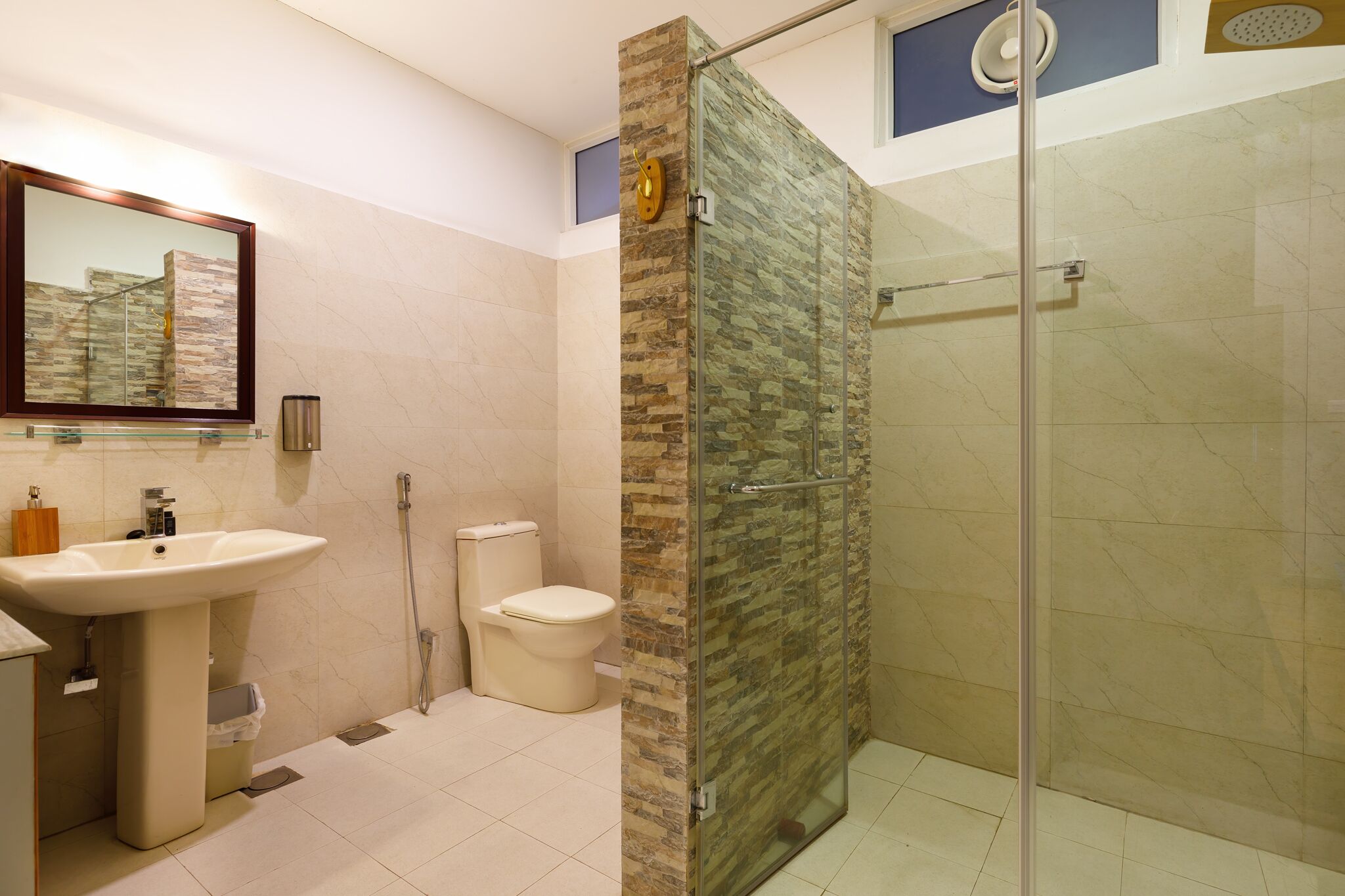 A modern bathroom with a glass-enclosed shower, a sink, and a toilet.