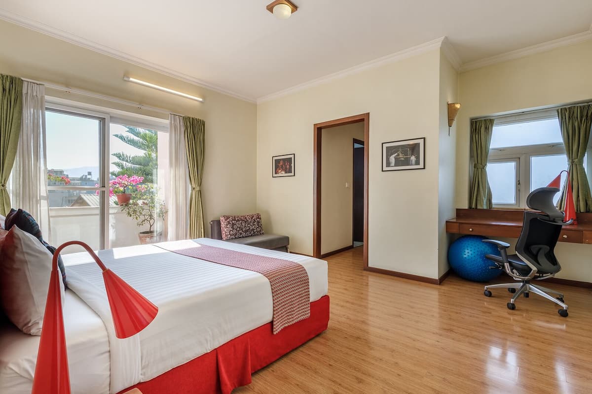A hotel room with a bed, a desk, a chair, and a window with curtains.