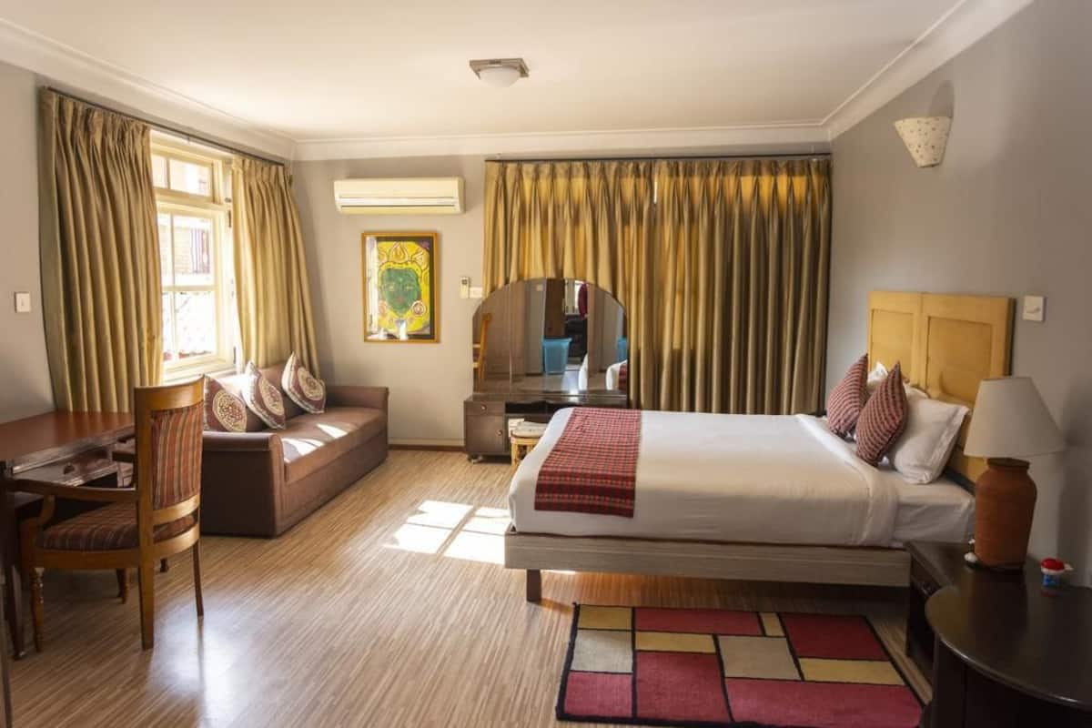 A hotel room with a bed, a sofa, a desk, and a chair.